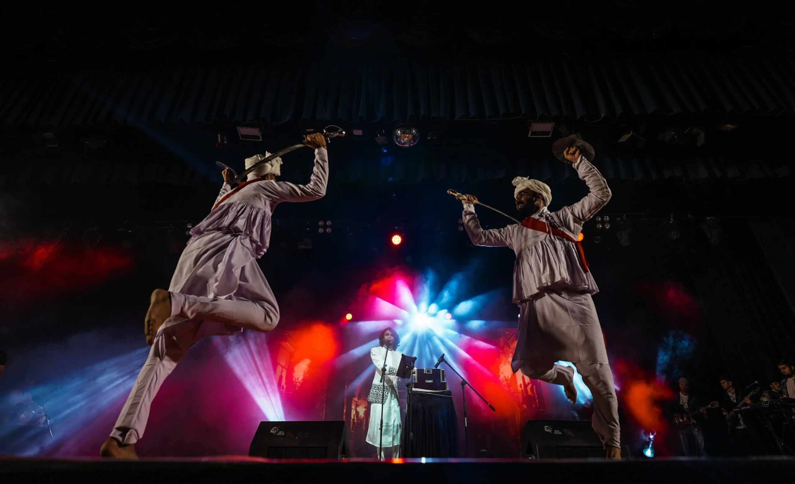 Rushabh Ahir and his troupe performing Gujarati folk live on a concert stage under dramatic lighting